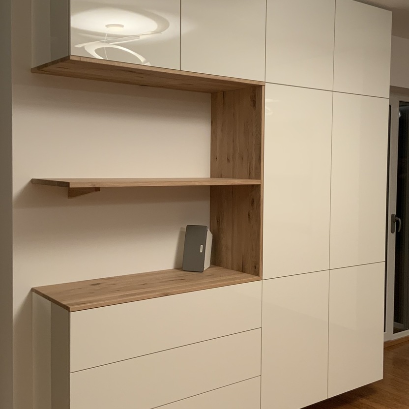 Ein moderner Schrank nach Maß, der geschlossene Hochglanzfächer mit offenen Holzregalen kombiniert. Die integrierten Schubladen und Regale bieten vielseitigen Stauraum.