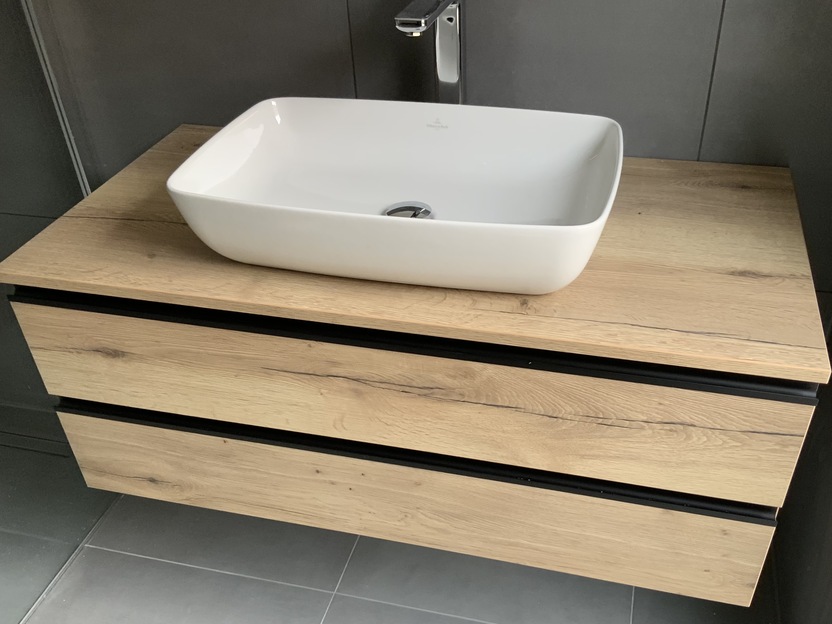 Unterschrank aus Holz unter weißem Waschbecken