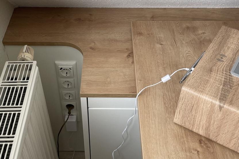 Detail Maßschreibtisch Holz Nahaufnahme eines maßgefertigten Holzschreibtischs mit Ausschnitt für Steckdosen und Heizung.