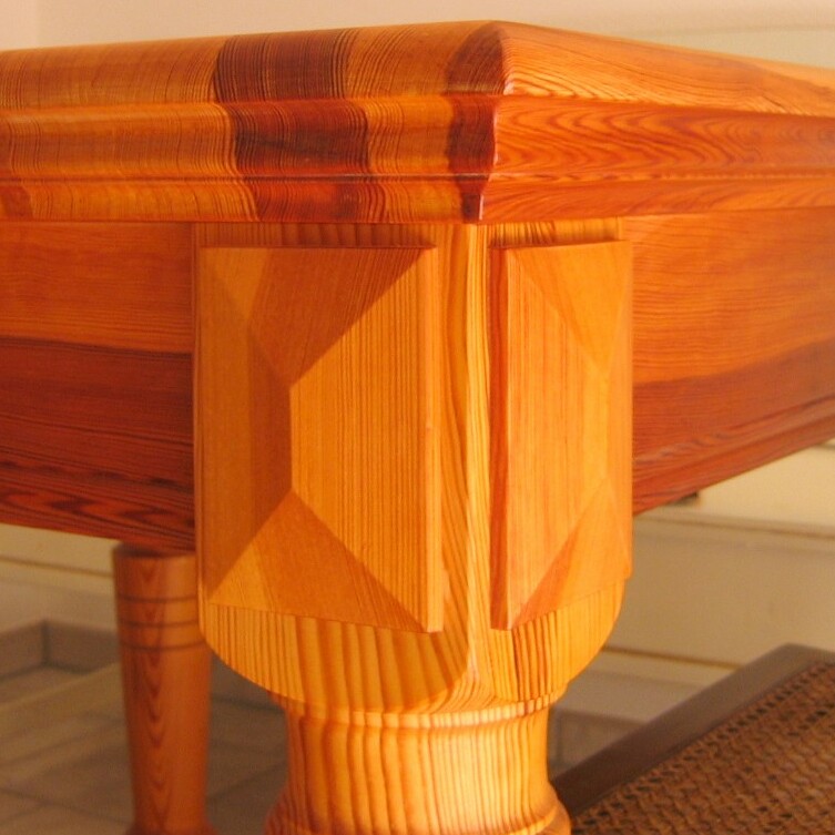 Edler Holztisch mit profilierten Beinen und abgerundeter Tischkante in warmem Farbton.