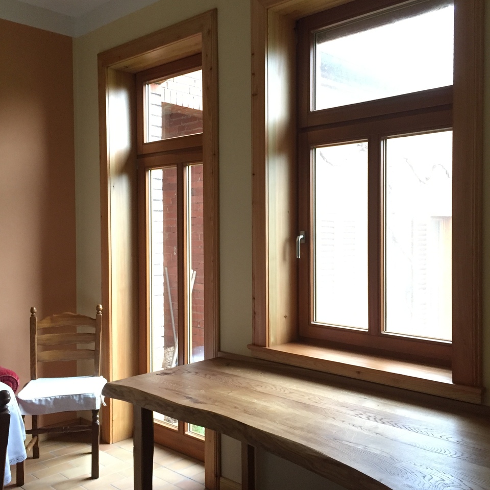 Heller Raum mit gro&szlig;en Fenstern und handgefertigtem Tisch aus massiver Eiche.