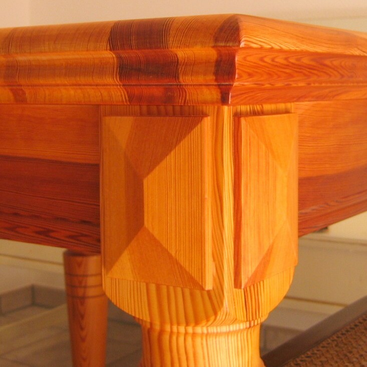 Edler Holztisch mit profilierten Beinen und abgerundeter Tischkante in warmem Farbton.