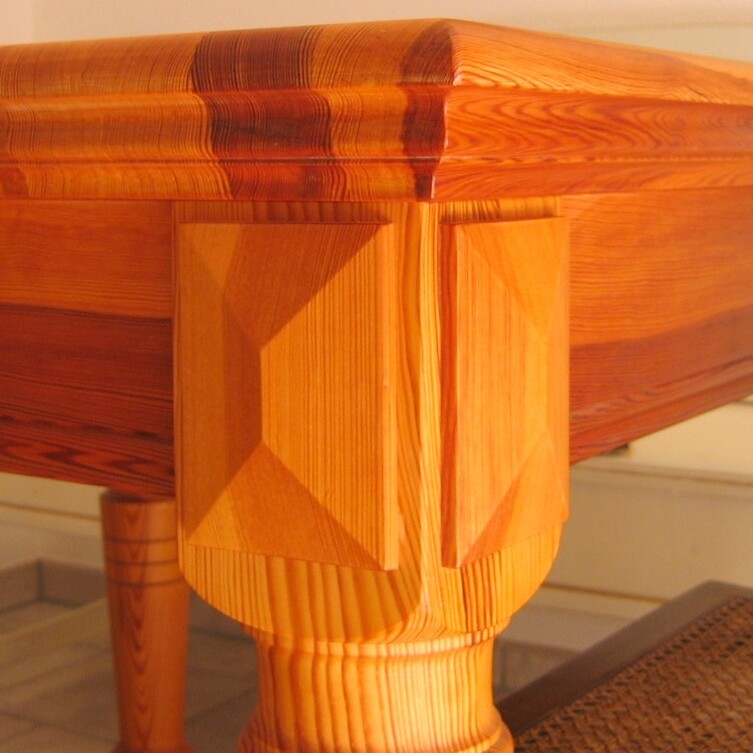 Edler Holztisch mit profilierten Beinen und abgerundeter Tischkante in warmem Farbton.