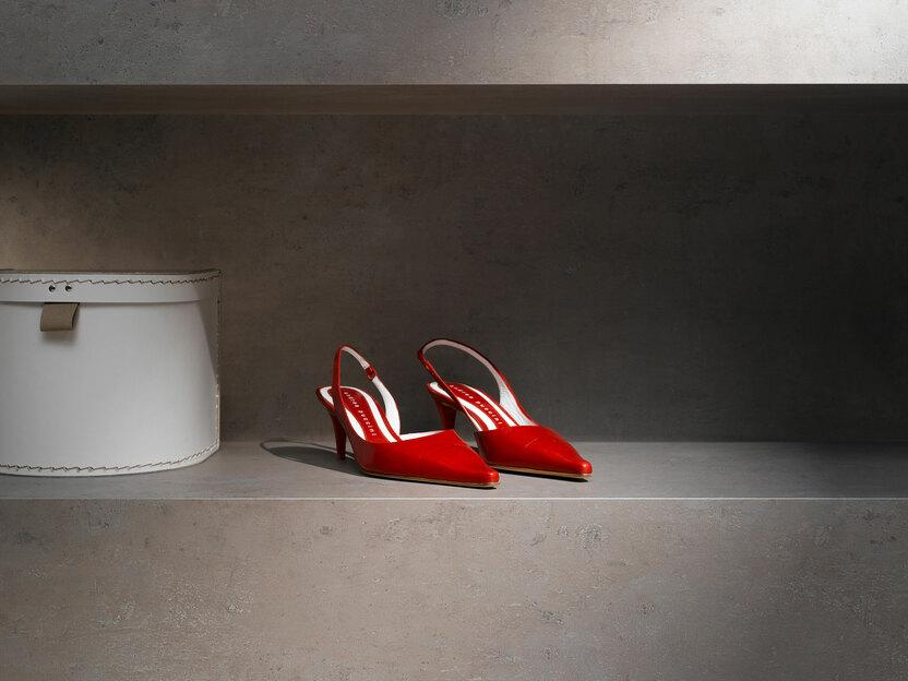 Detailaufnahme eines Ladenregals in Betonoptik mit Kontrast durch rote Absatzschuhe