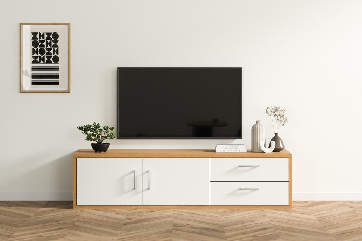 Elegante Kommode nach Maß im stilvollen Wohnzimmer Eine maßgeschneiderte Kommode in hellem Holzfinish mit weißen Fronten, darunter ein TV-Gerät, begleitet von dekorativen Vasen und Büchern, in einem hellen Wohnraum.