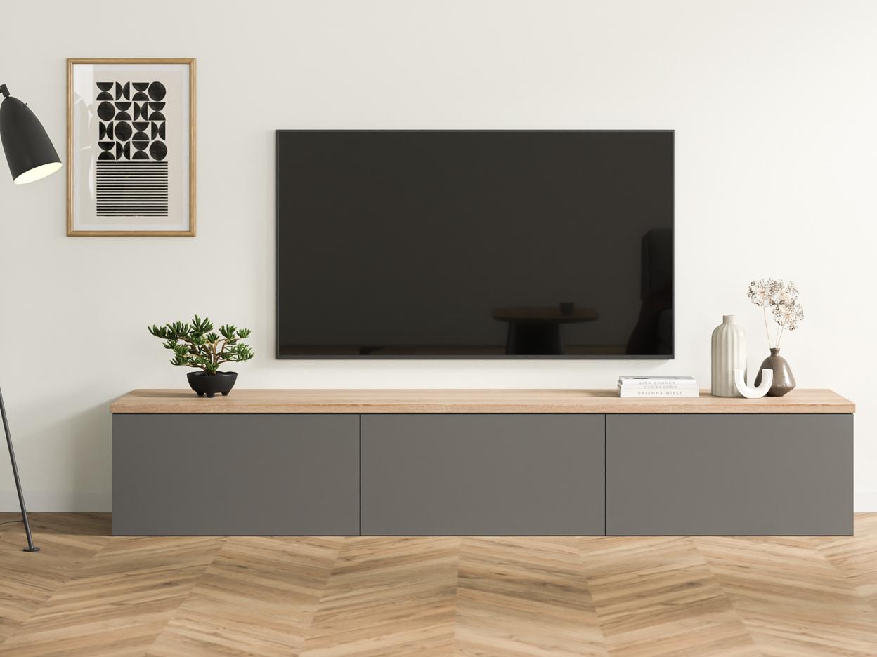 Maßgefertigte, dunkelgraue Kommode unter einem Flachbildfernseher, kombiniert mit einer warmen Holzplatte, minimalistischer Dekoration und einem schwarzen Stehlampe daneben.